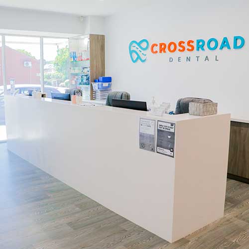 Dental clinic reception desk with Crossroad Dental logo on the wall behind